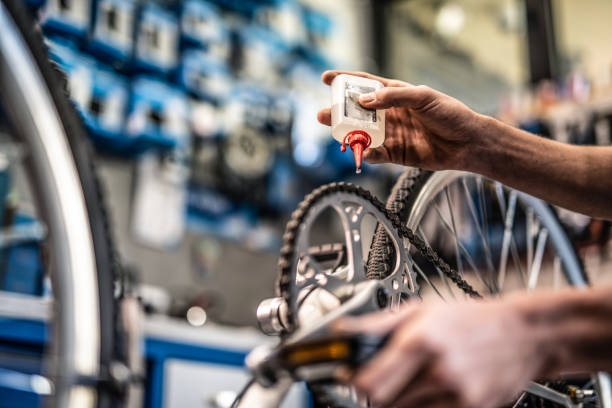 Mechanic putting oil on bicycle chain close up.