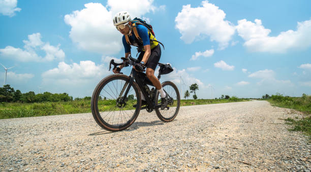 Asian man riding bicycle on gravel road at high speed