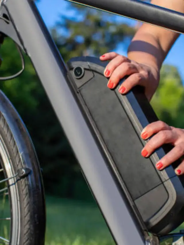 woman holding an electric bike battery mounted on frame