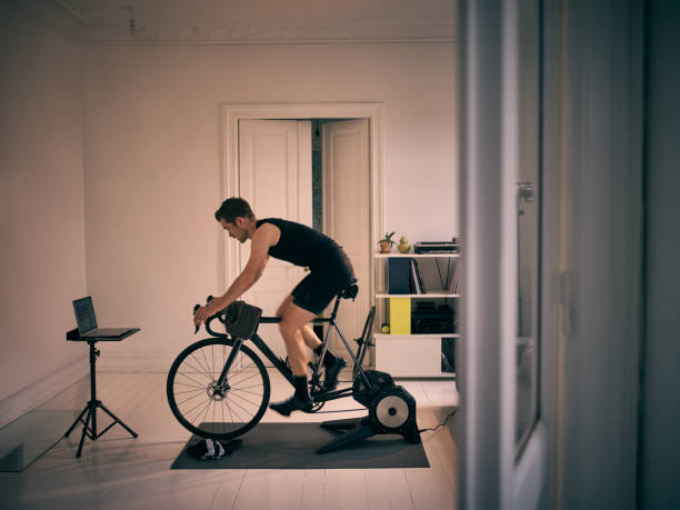 Shot of a young man working out on an exercise bike at home