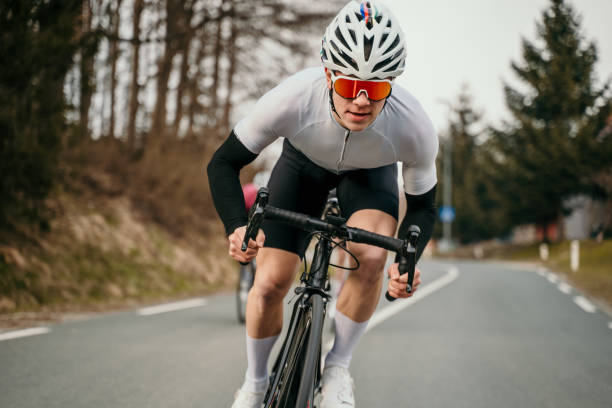 Professional cyclist racing on the road on cloudy day in winter.